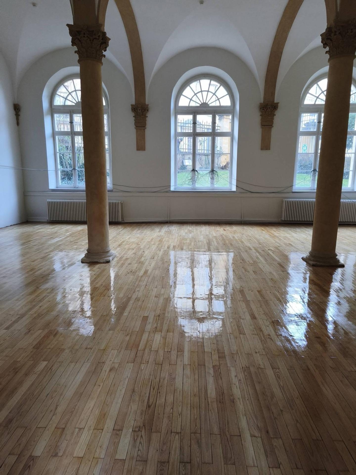 Salle voûtée à colonnes, fenêtres cintrées et parquet vitrifié